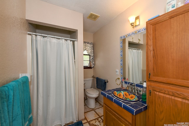 bathroom with tile floors, oversized vanity, and toilet