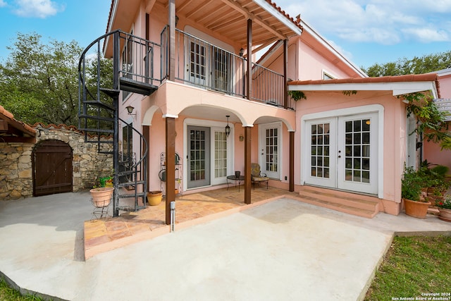 rear view of property featuring french doors, a balcony, and a patio