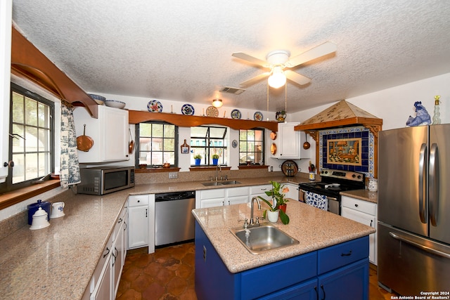 kitchen featuring blue cabinets, sink, white cabinetry, stainless steel appliances, and an island with sink