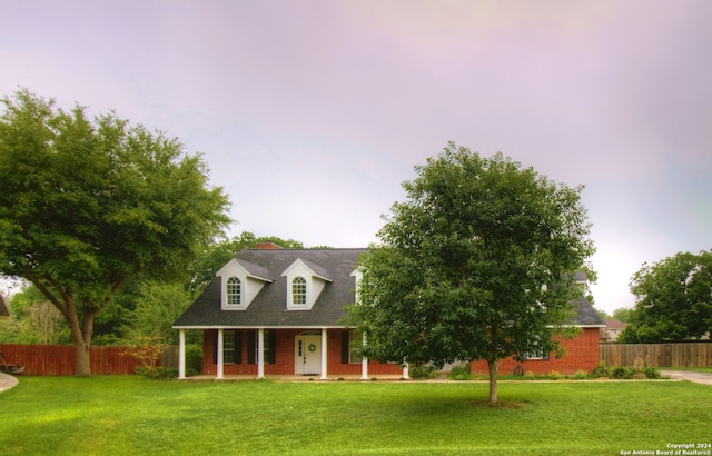 cape cod house with a front yard and a porch