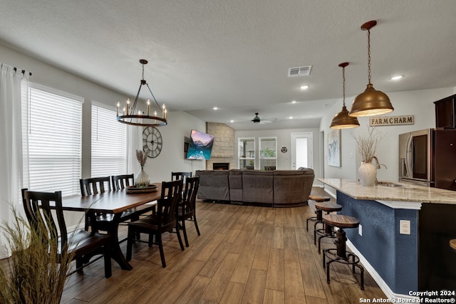 dining room with sink, a textured ceiling, dark hardwood / wood-style floors, and ceiling fan with notable chandelier