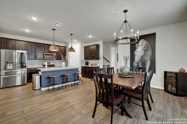 dining space with light wood-type flooring, a chandelier, and beverage cooler