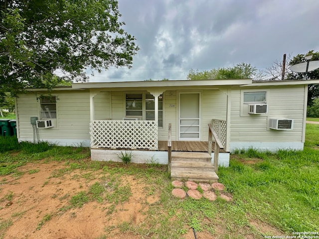 view of front of property with a wall unit AC and a porch