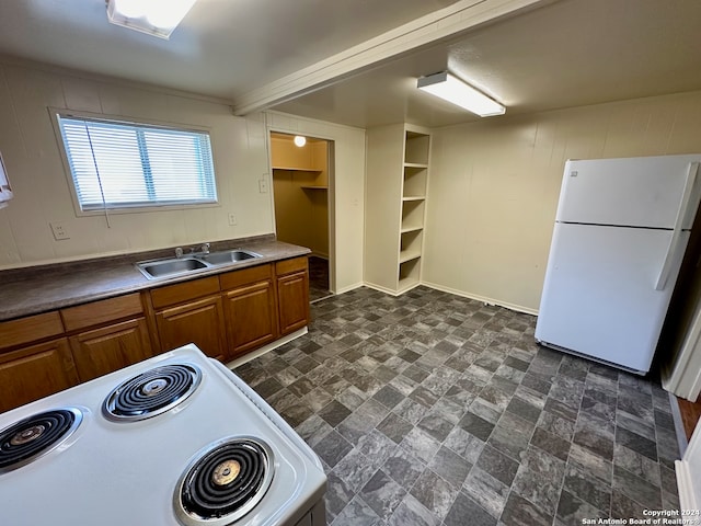 kitchen featuring sink, dark tile floors, white fridge, and range