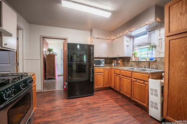 kitchen featuring sink, gas range oven, backsplash, black fridge, and dark hardwood / wood-style floors