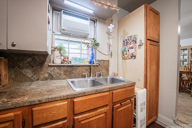 kitchen with backsplash, tile flooring, a wall mounted air conditioner, and sink