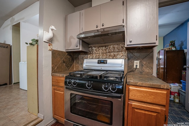 kitchen with backsplash, stainless steel range with gas stovetop, washer / clothes dryer, and light tile floors