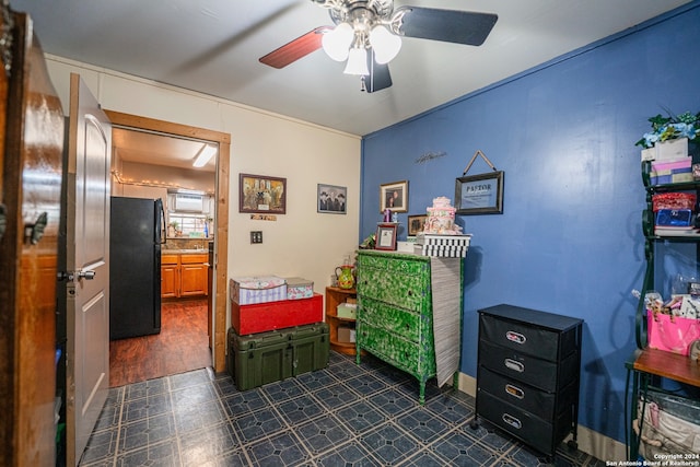 interior space with dark tile flooring, ceiling fan, and black refrigerator