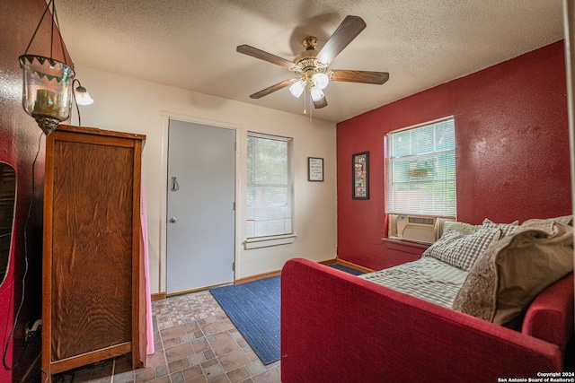 living room featuring a healthy amount of sunlight, dark tile floors, ceiling fan, and a textured ceiling