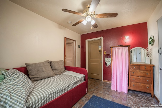 bedroom with a textured ceiling, ceiling fan, and tile flooring