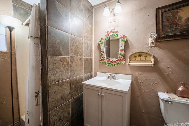 bathroom with vanity with extensive cabinet space, toilet, and tile walls