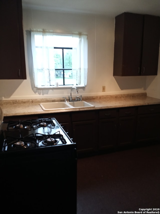 kitchen featuring stove, dark brown cabinets, and sink