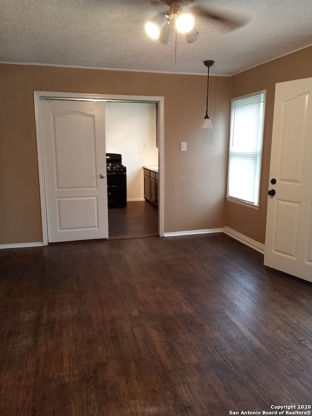 empty room featuring ceiling fan, dark wood-type flooring, and a textured ceiling