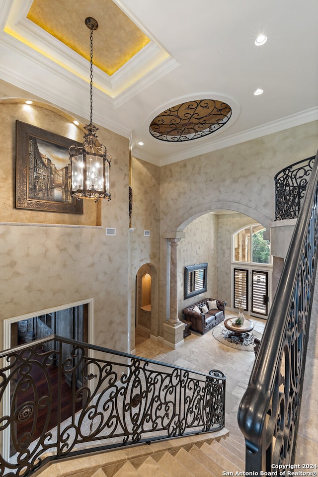 staircase featuring crown molding, an inviting chandelier, and decorative columns