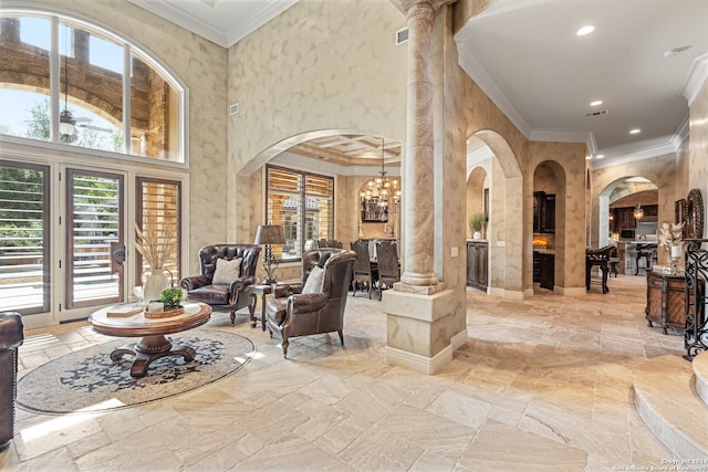 tiled living room with a chandelier, crown molding, a towering ceiling, and decorative columns