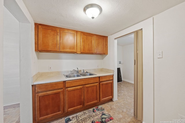 kitchen featuring sink, light tile floors, and a textured ceiling