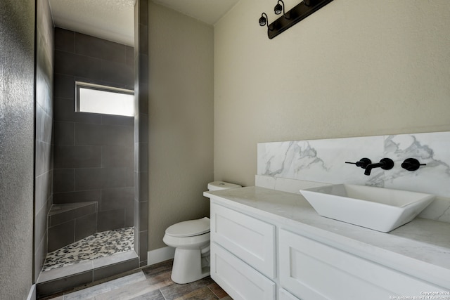 bathroom featuring tiled shower, vanity, and toilet