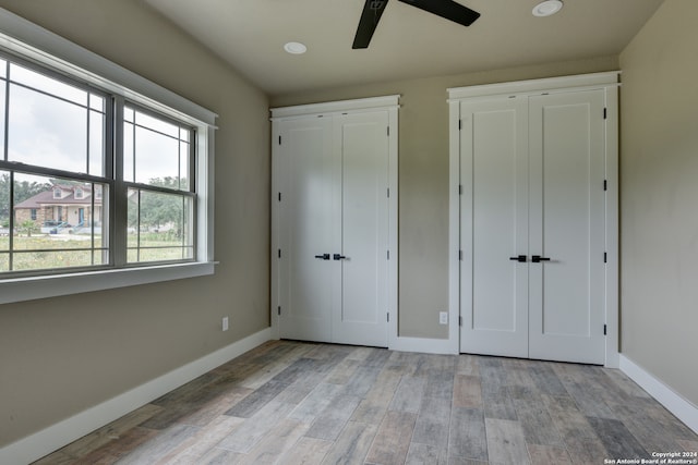 unfurnished bedroom with two closets, ceiling fan, and light hardwood / wood-style floors