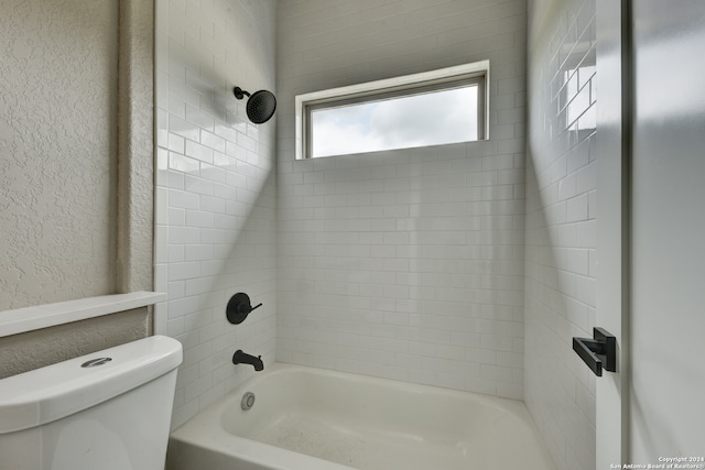 bathroom with tiled shower / bath combo and toilet