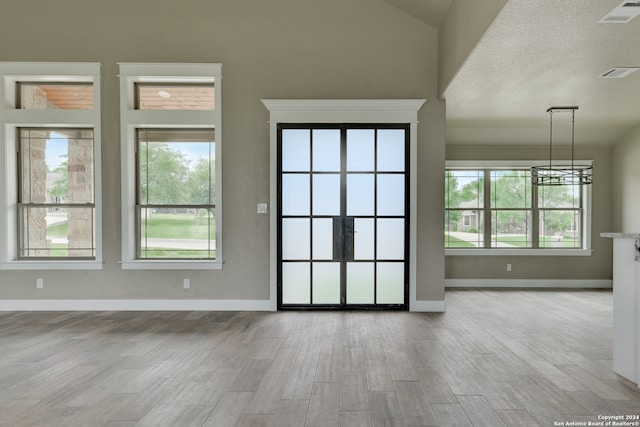 interior space with wood-type flooring, a textured ceiling, high vaulted ceiling, and an inviting chandelier