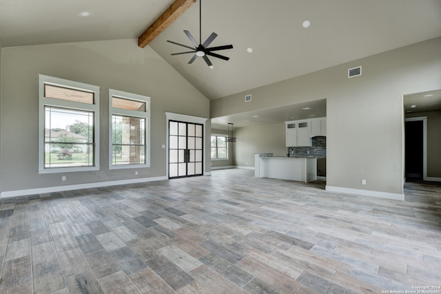 unfurnished living room with ceiling fan, light hardwood / wood-style flooring, beam ceiling, and high vaulted ceiling