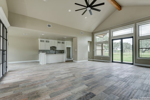 unfurnished living room featuring beamed ceiling, light hardwood / wood-style floors, ceiling fan, and high vaulted ceiling