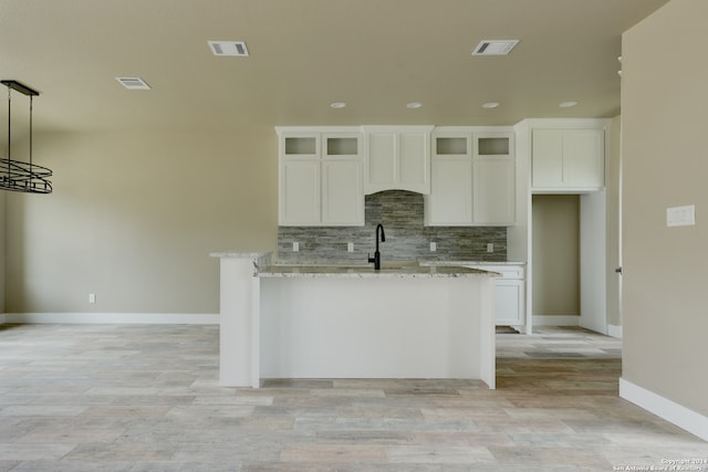 kitchen featuring white cabinetry, pendant lighting, and light stone countertops