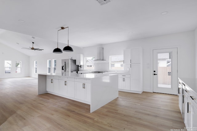 kitchen with a kitchen island, a wealth of natural light, light hardwood / wood-style floors, and wall chimney range hood