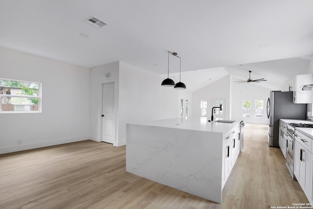 kitchen with white cabinets, sink, light hardwood / wood-style floors, and an island with sink