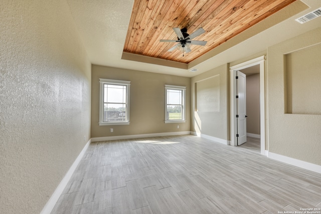 empty room with wood ceiling, ceiling fan, a raised ceiling, and light wood-type flooring