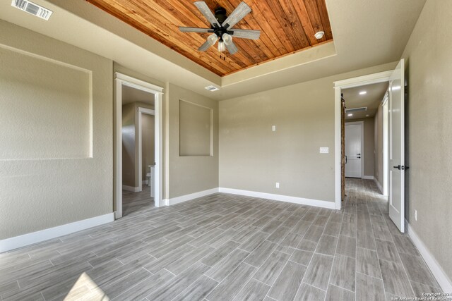 unfurnished room featuring ceiling fan, a raised ceiling, and wood ceiling