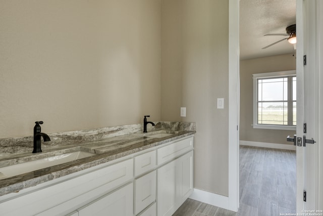 bathroom featuring hardwood / wood-style flooring, a textured ceiling, ceiling fan, and dual vanity