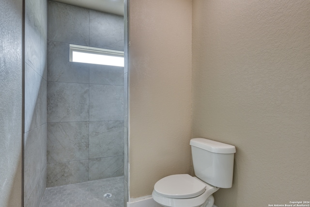 bathroom featuring a tile shower and toilet