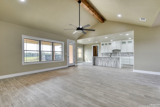 unfurnished living room with high vaulted ceiling, beam ceiling, ceiling fan, and sink