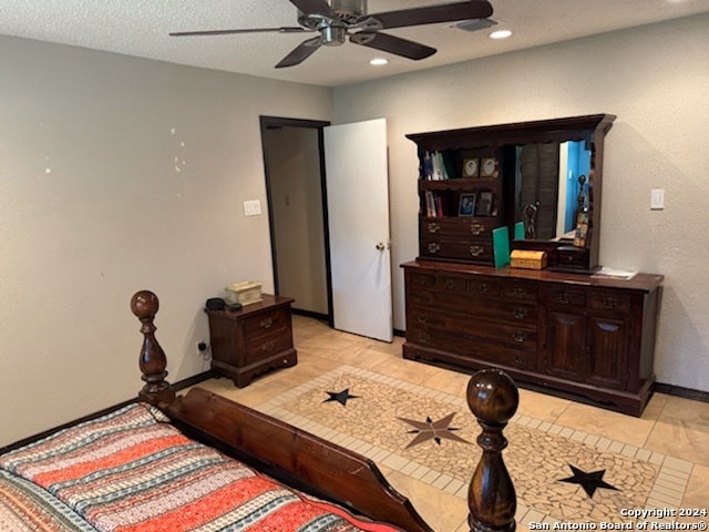 bedroom with a textured ceiling, light tile patterned floors, and ceiling fan