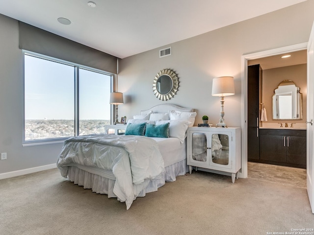 bedroom with ensuite bath, light colored carpet, and sink