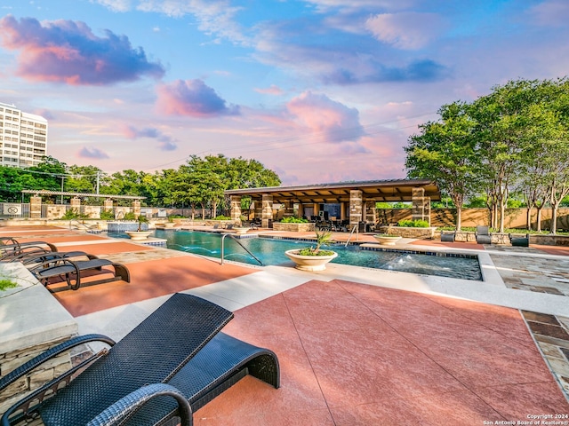 pool at dusk with a patio area and pool water feature