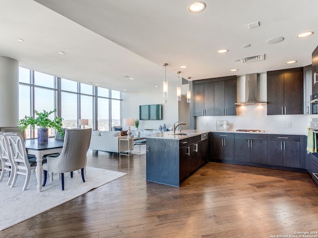 kitchen featuring wood-type flooring, sink, kitchen peninsula, and wall chimney exhaust hood