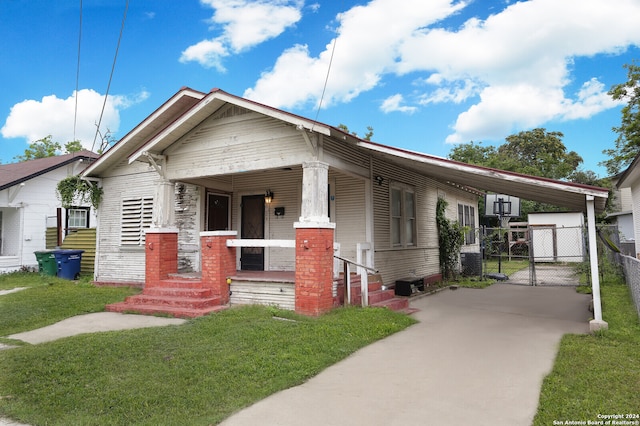 view of front facade with a carport, a porch, and a front lawn