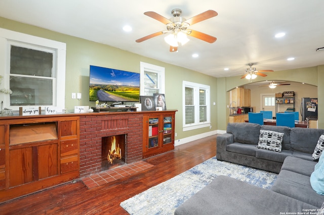 living room with dark hardwood / wood-style flooring, ceiling fan, and a fireplace