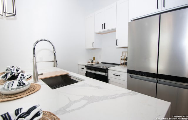 kitchen featuring appliances with stainless steel finishes, light stone counters, sink, and white cabinetry