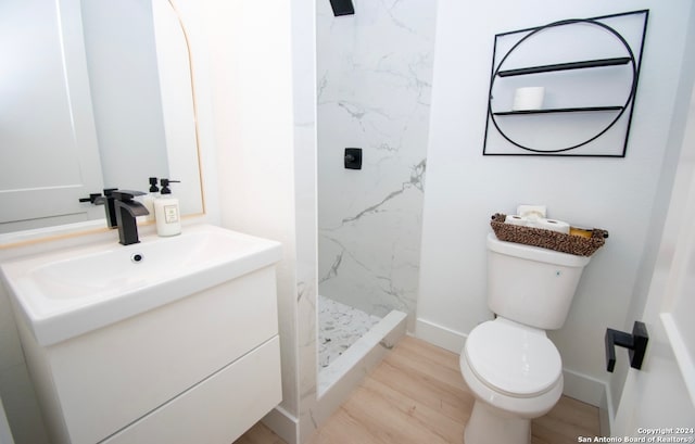 bathroom featuring oversized vanity, hardwood / wood-style flooring, toilet, and tiled shower