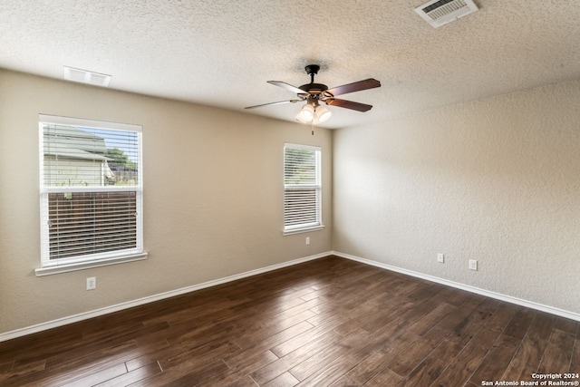 spare room featuring plenty of natural light, dark hardwood / wood-style flooring, ceiling fan, and a textured ceiling