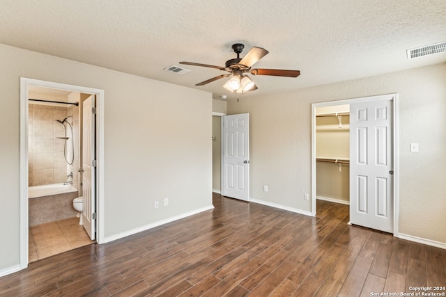 unfurnished bedroom with a closet, ceiling fan, a textured ceiling, ensuite bath, and a walk in closet