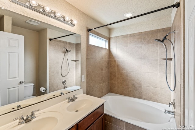 full bathroom with tiled shower / bath combo, a textured ceiling, toilet, and double vanity