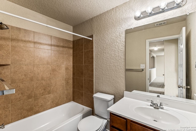 full bathroom with tiled shower / bath, vanity, toilet, and a textured ceiling