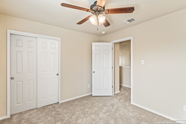 unfurnished bedroom featuring light colored carpet, ceiling fan, and a closet