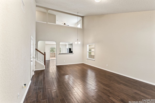 unfurnished living room with dark hardwood / wood-style floors, high vaulted ceiling, and a textured ceiling