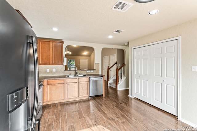 kitchen with a textured ceiling, sink, tasteful backsplash, hardwood / wood-style floors, and stainless steel appliances