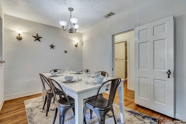 dining room with a textured ceiling, hardwood / wood-style floors, and a notable chandelier